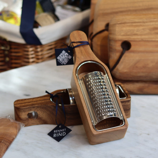 Wooden cheese grater with metal grating surface on a white surface