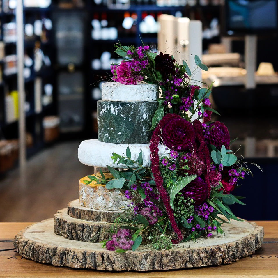 Attenborough cheese tower with five tiers of British artisan cheese and purple flowers