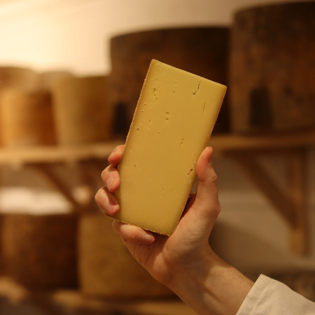 Cheesemonger holding a hand-cut wedge of Burford at Rennet & Rind.