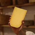 Hand-cut Connage Gouda British artisan cheese held by a cheesemonger at Rennet & Rind.