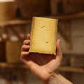 Hand-cut Ducketts Caephilly British artisan cheese held by a cheesemonger at Rennet & Rind.