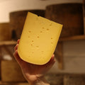 Hand-cut Mayfield British artisan cheese held by a cheesemonger at Rennet & Rind.