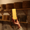 Hand-cut Ogleshield British artisan cheese held by a cheesemonger at Rennet & Rind.