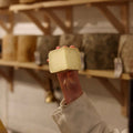Cheesemonger holding freshly cut piece of British Artisan Sheeps cheese, Rustler, at Rennet & Rind