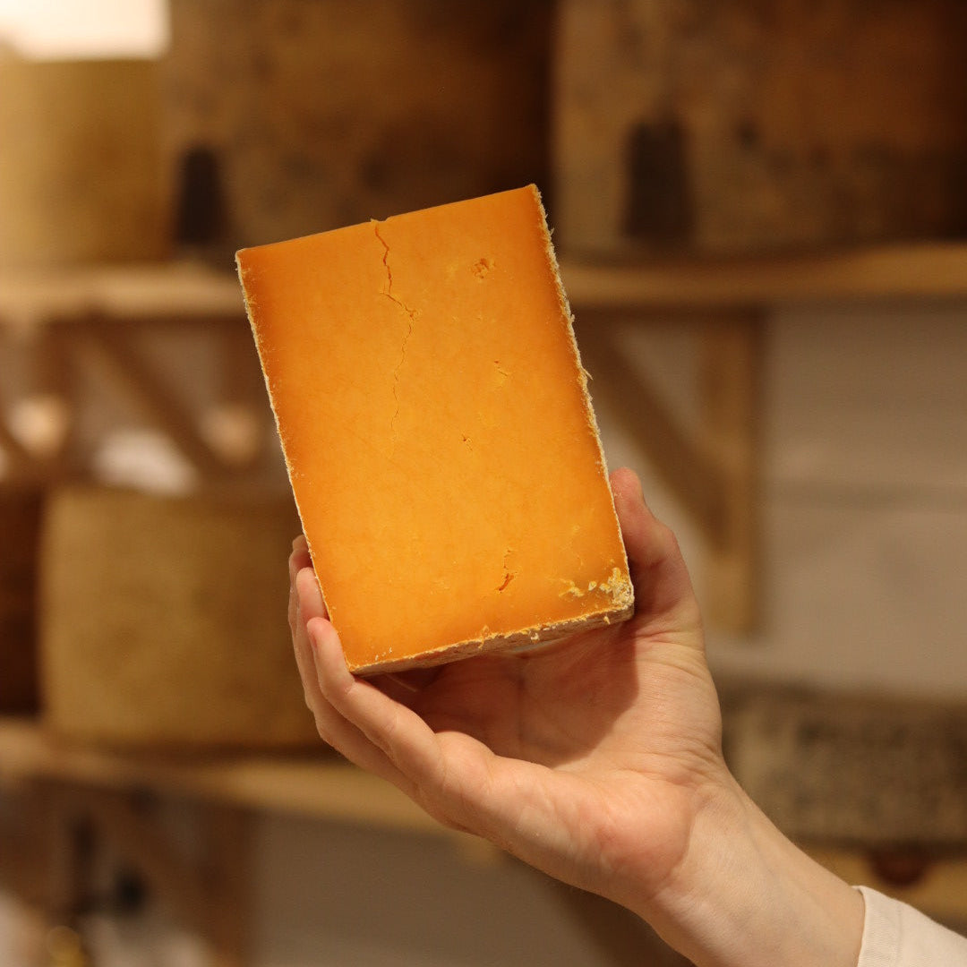 Rennet & Rind cheesemonger holding piece of British Artisan Cheese Sparkenhoe Red Leicester 