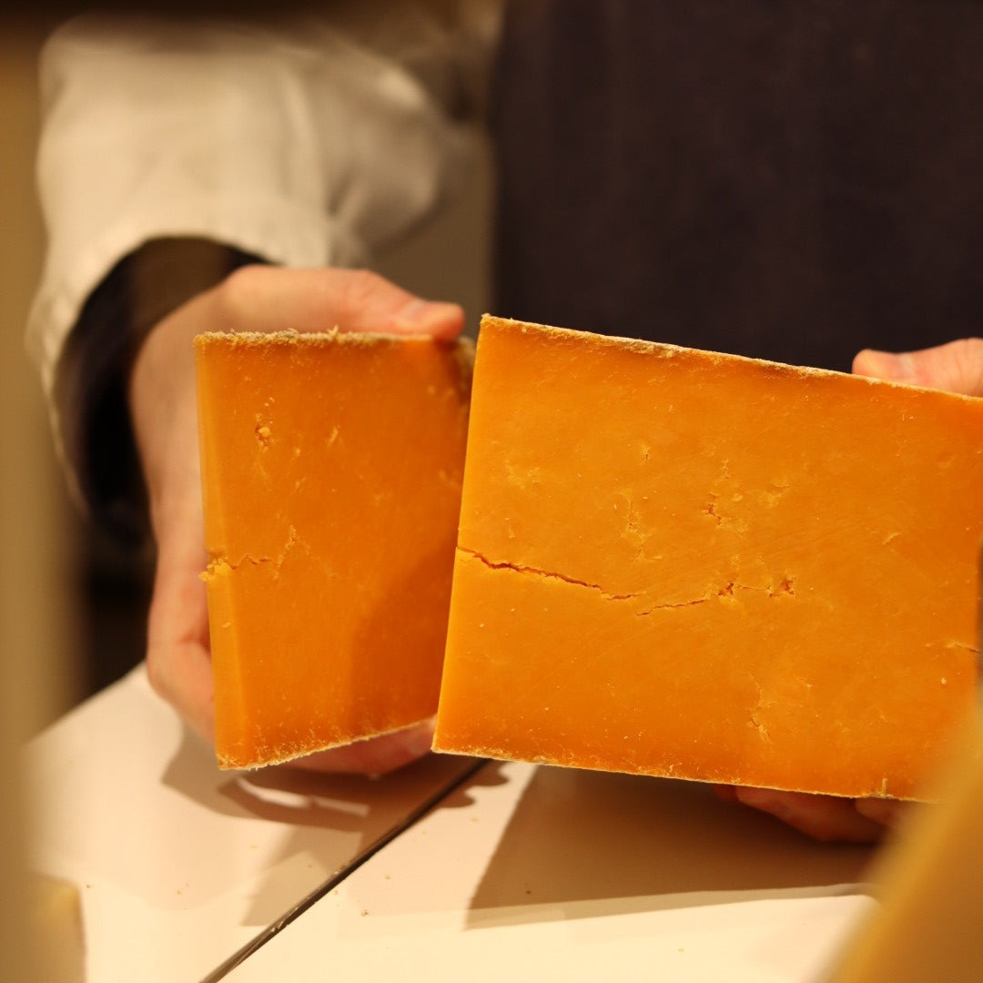 Rennet & Rind cheesemonger cutting wedge of British artisan cheese, Sparkenhoe red Leicester