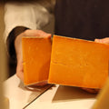 Rennet & Rind cheesemonger cutting wedge of British artisan cheese, Sparkenhoe red Leicester