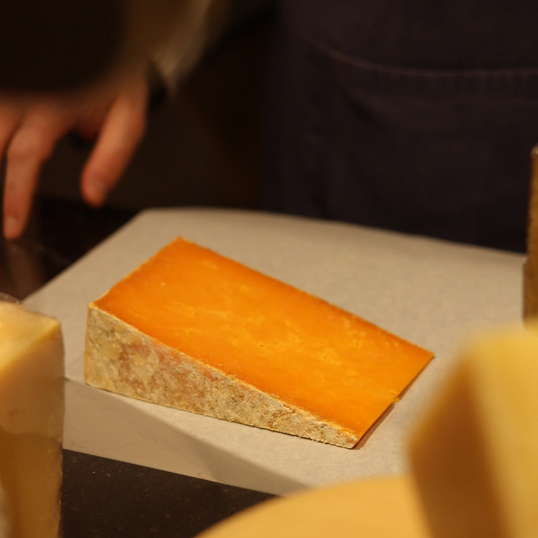 Rennet & Rind cheesemonger wrapping freshly cut piece of British Artisan Cheese, Sparkenhoe Red Leicester. 