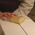 Rennet & Rind cheesemonger hand cutting piece of St Helena, British Artisan Cheese.