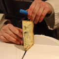 Rennet & Rind cheesemonger cutting a piece of British artisan blue cheese, Stichelton for customer 