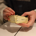 Cheesemonger cutting a piece of British artisan blue cheese 'The Duke' for customer at Rennet & Rind.